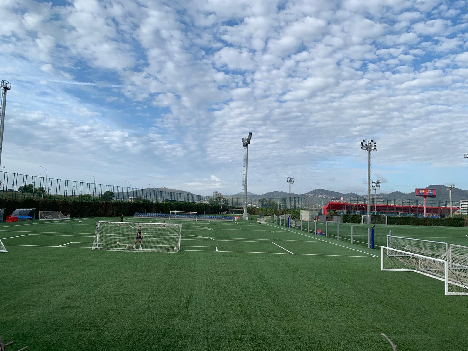 A turf training complex with goals and players warming up in the distance